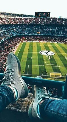 a person's feet are sitting on the edge of a railing at a soccer stadium