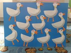 there are many white ducks on the blue background and one is standing in front of them