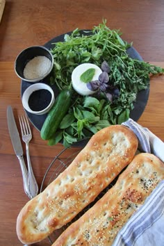 two bread sticks sitting on top of a table next to a bowl of salad and fork