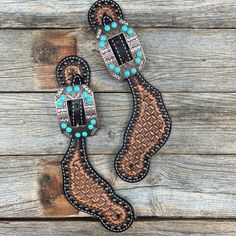 two leather boots with turquoise stones and beaded accents on them sitting on a wooden surface