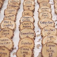 many wooden slices with names on them sitting on a white table cloth covered tablecloth