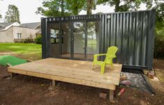 a green chair sitting on top of a wooden platform in front of a shipping container