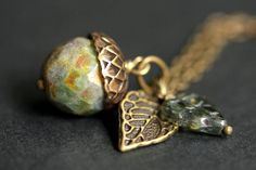 A handmade acorn necklace designed from a rainforest green glass crystal with a hint of mottled brown accents that has been combined with a detailed bronze leaf and green Czech glass leaf charm. If you would like a length of chain different than offered, please contact me for pricing. Check out the other colors if acorn necklaces offered in my shop! http://etsy.me/1iMZM8w Stop by and visit http://stumblingonsainthood.etsy.com to see more handmade designs! © Stumbling On Sainthood (StumblingOnSai Acorn Jewelry, Oak Leaf Necklace, Acorn Ornaments, Acorn Pendant, Bronze Green, Acorn And Oak, Acorn Necklace, Feminine Jewelry, Nature Inspired Jewelry