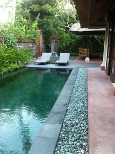 a small pool in the middle of a patio area with lounge chairs and plants around it