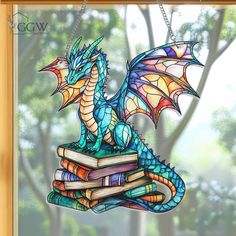 a stained glass dragon sitting on top of a stack of books