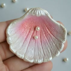 a close up of a person's hand holding a flower with pearls on it