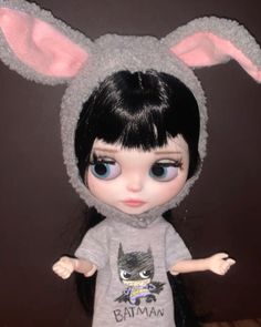 the doll is wearing a gray shirt with ears