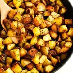 cooked potatoes in a skillet with a wooden spoon