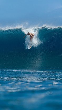 a man riding a wave on top of a surfboard in the middle of the ocean