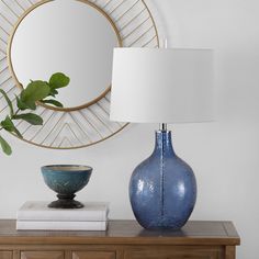 a blue vase sitting on top of a wooden table next to a white lampshade