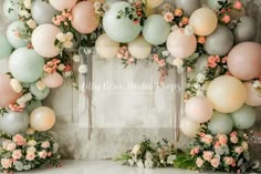 an arrangement of pastel balloons and flowers are arranged in the shape of a wreath