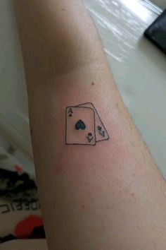 a person with a tattoo on their arm holding up a playing card