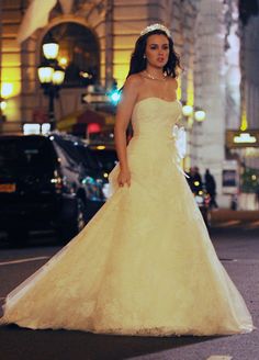 a woman in a wedding dress is walking down the street at night with her hand on her hip