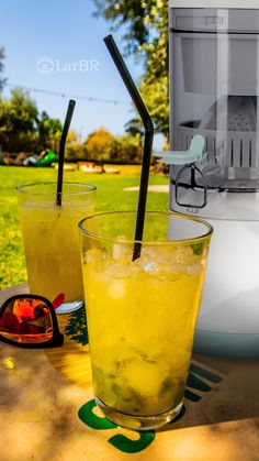 two glasses filled with yellow liquid sitting on top of a table