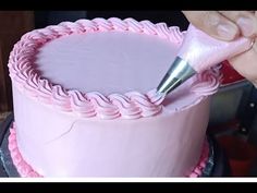 someone is decorating a pink cake with icing