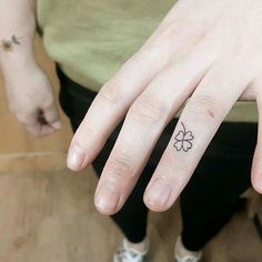 a person's hand with a small clover tattoo on their left thumb and finger