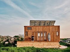 a person standing on the porch of a tiny house made out of wood and metal