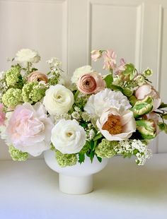 a white vase filled with lots of pink and white flowers