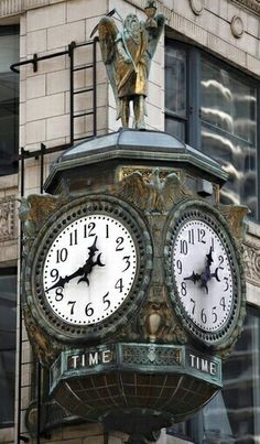 a large clock on the side of a building with roman numerals and a statue