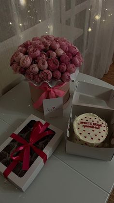 a box of pink roses and a cake on a table