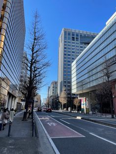 an empty city street with tall buildings in the background and people walking on the sidewalk