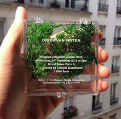 a person holding up a clear plastic case with plants in it and the words dries van noten on it