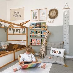 a young child sitting on the floor reading a book in a room with stuffed animals