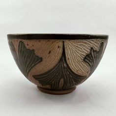 a brown and black bowl sitting on top of a white table