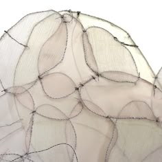 an artistic sculpture made out of wire and fabric with leaves on the top, in front of a white background