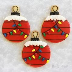 three decorated christmas ornaments hanging from strings