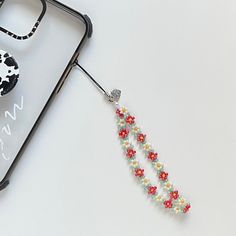 a cell phone with some beads on it next to a pair of scissors and a case