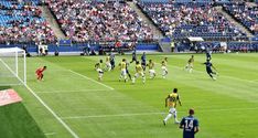 a group of people playing soccer on a field with fans in the stands behind them