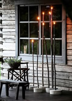 candles are lit in front of a window on a porch