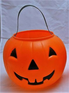 an orange plastic pumpkin bucket with black eyes