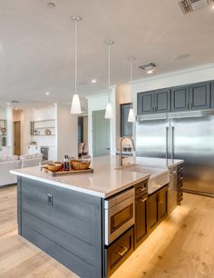 a large kitchen with an island in the middle and stainless steel appliances on both sides