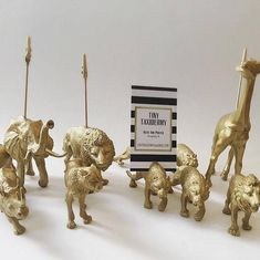 small gold figurines are standing next to each other with a sign in the background