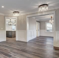 an empty living room with wood floors and chandeliers