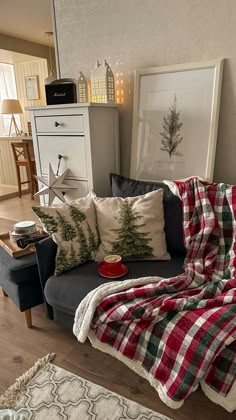 a living room filled with furniture covered in blankets and christmas tree pillow cases on top of the couch