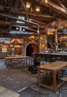 an old brick building with tables and stools in front of the bar area,