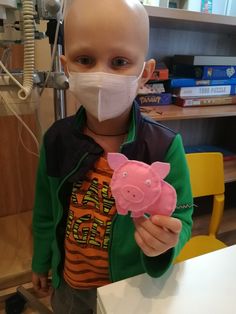 a young boy wearing a face mask and holding a pig toy