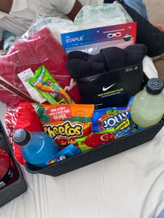 a basket filled with snacks and drinks on top of a bed next to another bag