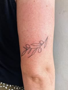 a woman's arm with an olive branch tattoo on the left side of her arm