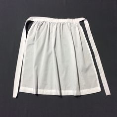 a white skirt on a black background with the bottom part pulled up to show it's pleating