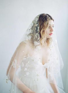 a woman wearing a wedding veil with flowers on it