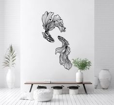 a fish wall decal in a room with white walls and flooring, along with potted plants