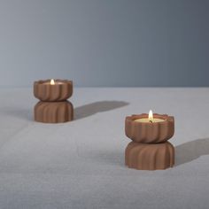 two small candles sitting next to each other on top of a white tablecloth covered floor