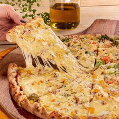 a person taking a slice of pizza from a wooden platter