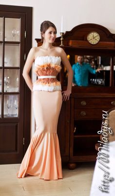 a woman in a dress standing next to a dresser