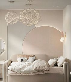 a white bed sitting under a large mirror in a room with lights on the ceiling