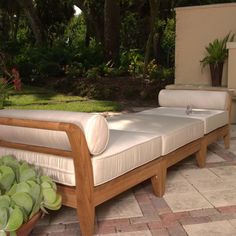 an outdoor patio with two wooden chaise lounges and potted plants on the side